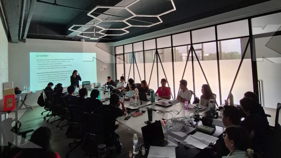 Participants follow the slides at long tables in a Kognifi Power of Business Communication Skills class