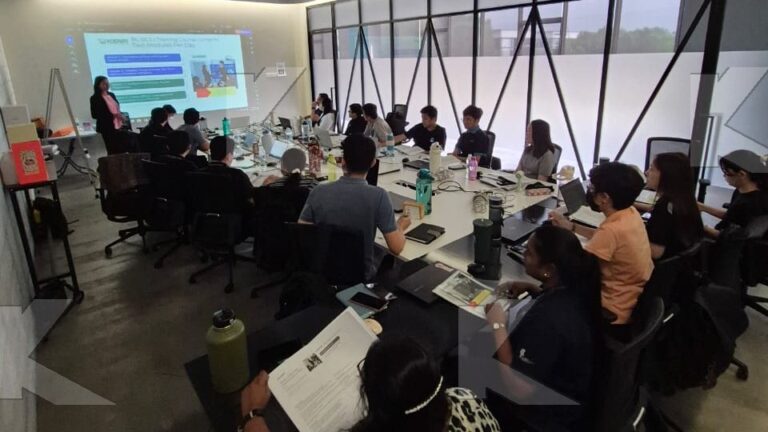 Trainer presents at the screen to a large in-house group in a Kognifi Power of Business Communication Skills class