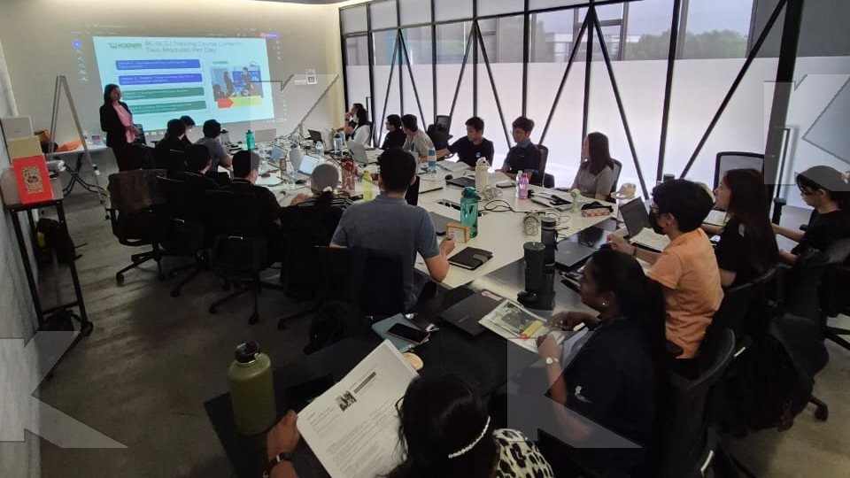 Trainer presents at the screen to a large in-house group in a Kognifi Power of Business Communication Skills class