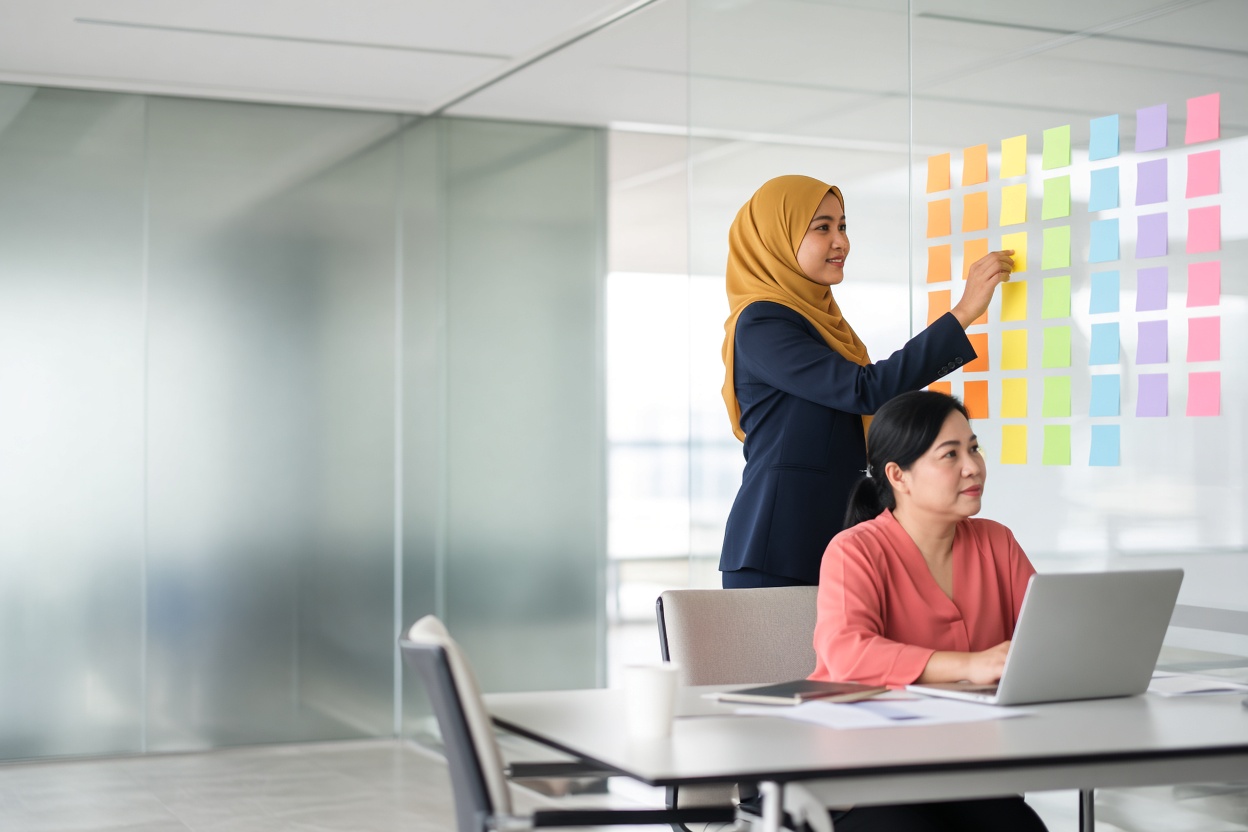 An HR manager and a team lead plan development paths at a wall of coloured notes.