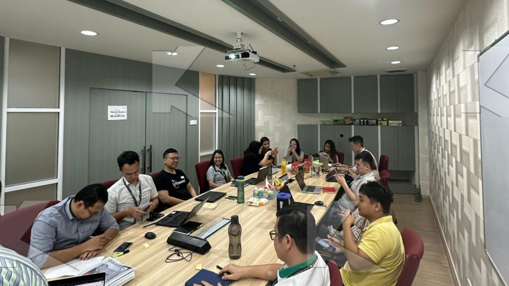 Participants work on a negotiation case at a long table in an in-house Kognifi Sales Negotiation class
