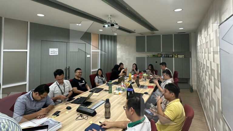 Participants work on a negotiation case at a long table in an in-house Kognifi Sales Negotiation class