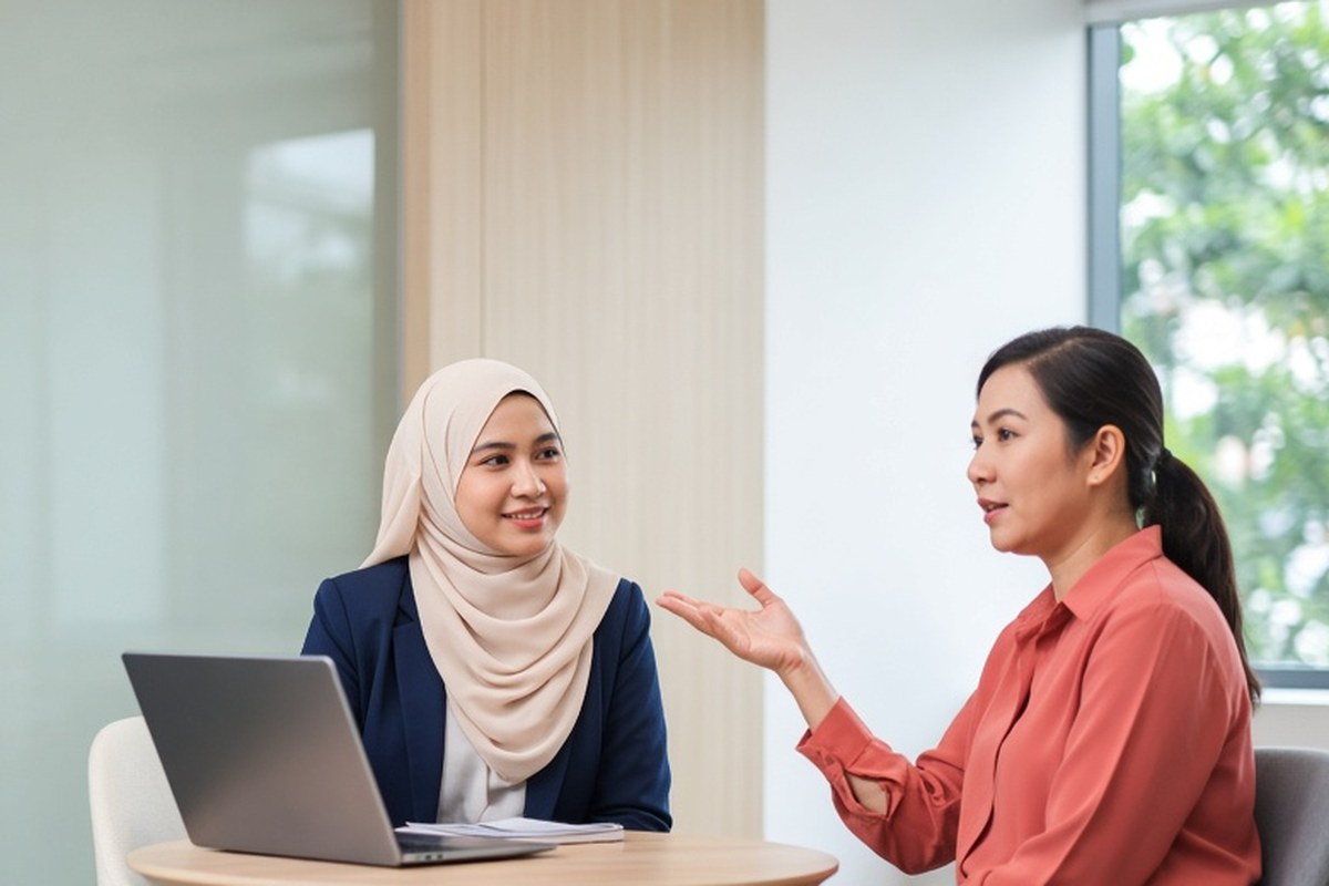 An HR officer asks a training adviser a question at a small round table.
